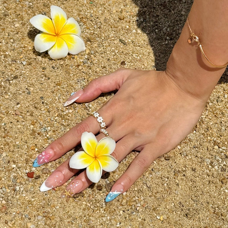 Fincloset Coastbloom press-on nails in almond shape, featuring tropical beach-themed nail art with 3D floral accents, pearls, starfish charms, and pastel blue and white French tips. Perfect summer press on nails for vacation, cute DIY manicure ideas, and ocean-inspired nail looks.