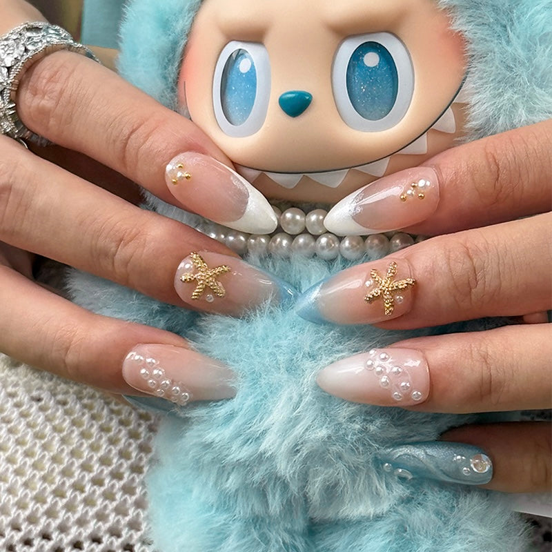 Fincloset Seanova handmade almond French tip press-on nails with ocean-inspired pearl and starfish designs, paired with Labubu plush figure for a playful summer vibe.