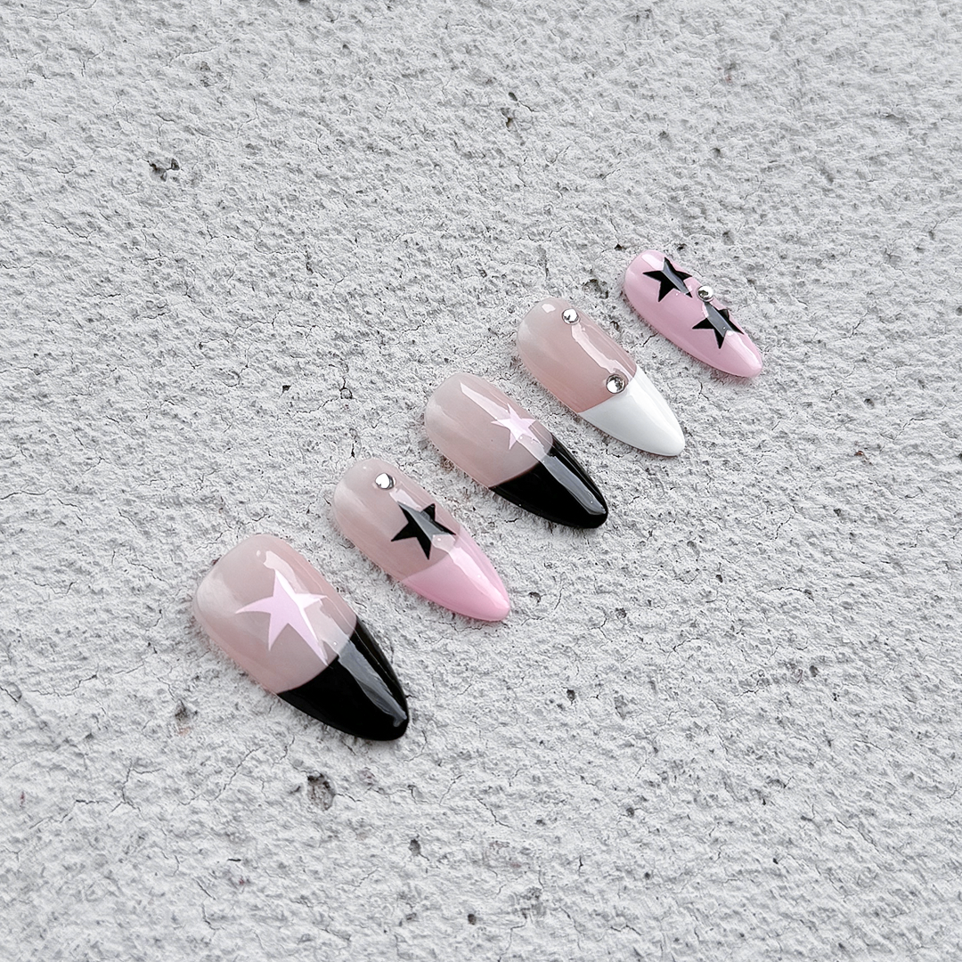 Handcrafted almond-shaped press-on nails in black and pink with bold star designs. Stylish and edgy for a striking look.