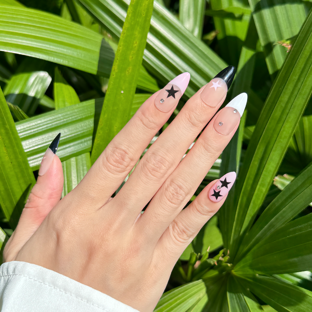 Handcrafted almond-shaped press-on nails in black and pink with bold star designs. Stylish and edgy for a striking look.