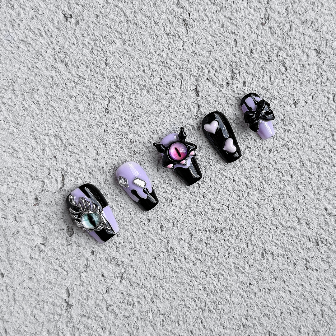 Handmade coffin-shaped press-on nails in black and candy purple with 3D devil eye decorations, offering a playful, sweet, and edgy style.