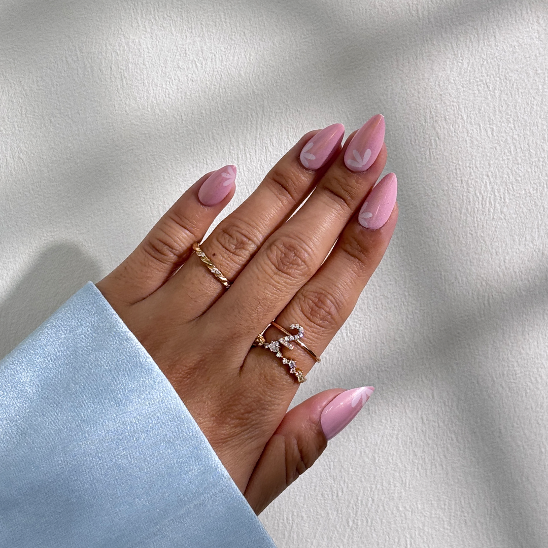 Fincloset soft pink natural almond-shaped press-on nails with yellow shimmer, fine glitter, and dainty white floral designs, creating a fresh, feminine, and radiant spring-inspired manicure.