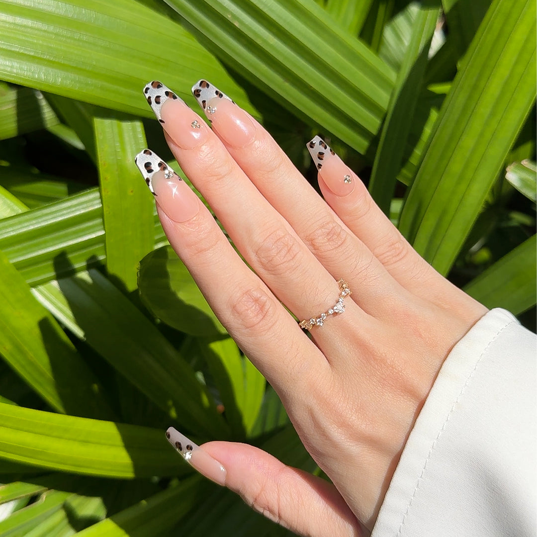 Handmade coffin-shaped press-on nails with silver French tips, brown cow print, and delicate diamond accents for a bold, stylish, and wild look.
