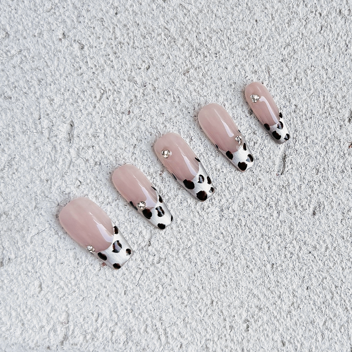 Handmade coffin-shaped press-on nails with silver French tips, brown cow print, and delicate diamond accents for a bold, stylish, and wild look.