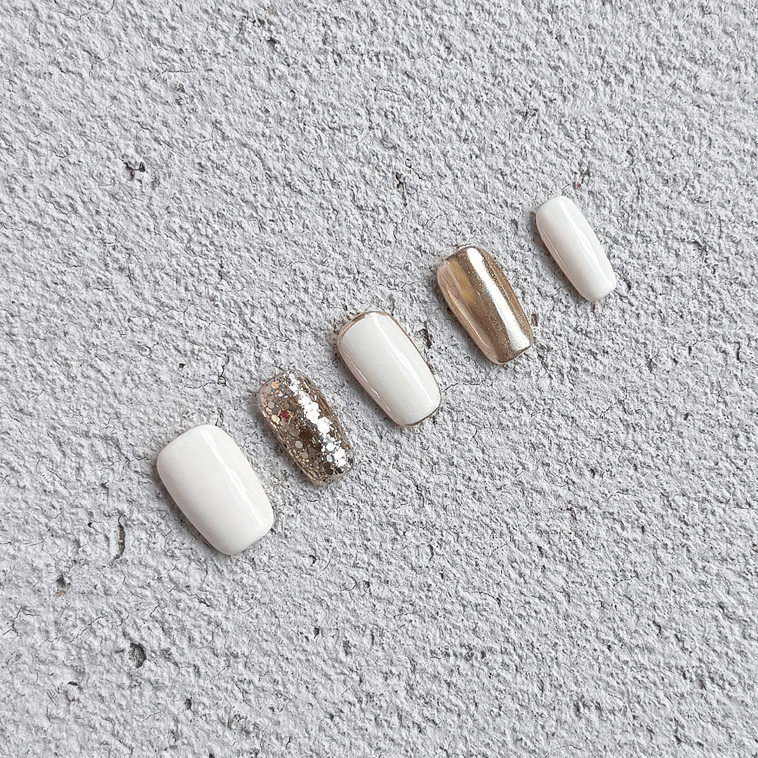 Ivory Luxe handmade square-shaped press-on nails in ivory and gold with sparkling gold glitter accents