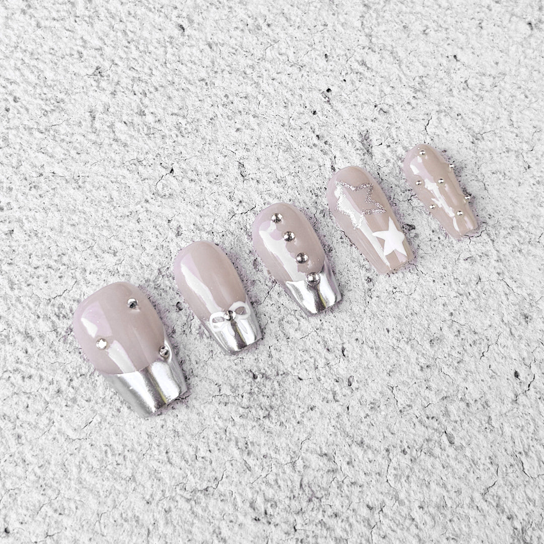 Handmade coffin-shaped press-on nails with metallic French tips, adorned with bow designs, rhinestones, and beads. A playful yet elegant style