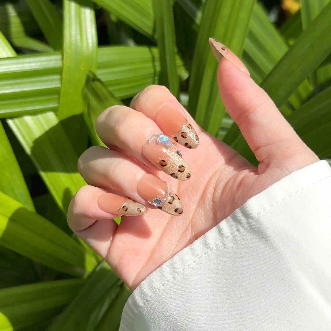 Fincloset handmade almond-shaped press-on nails with golden brown glossy French tips featuring shimmery cat-eye leopard print, blending elegance and boldness.