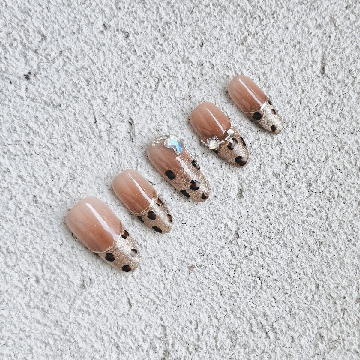 Fincloset handmade almond-shaped press-on nails with golden brown glossy French tips featuring shimmery cat-eye leopard print, blending elegance and boldness.