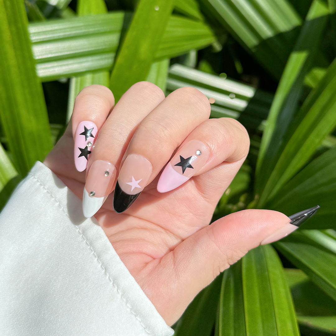 Handcrafted almond-shaped press-on nails in black and pink with bold star designs. Stylish and edgy for a striking look.