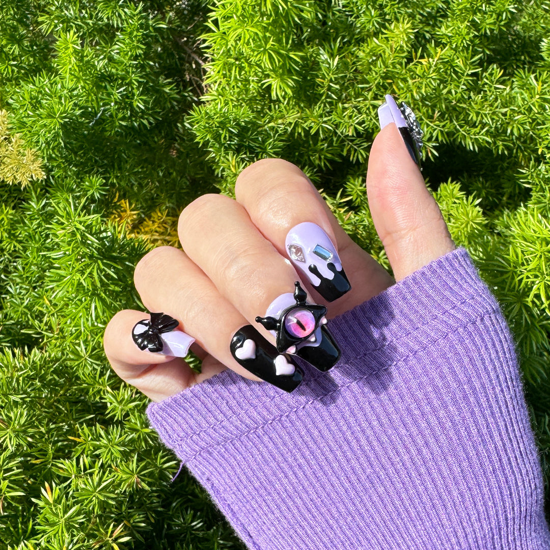 Handmade coffin-shaped press-on nails in black and candy purple with 3D devil eye decorations, offering a playful, sweet, and edgy style.