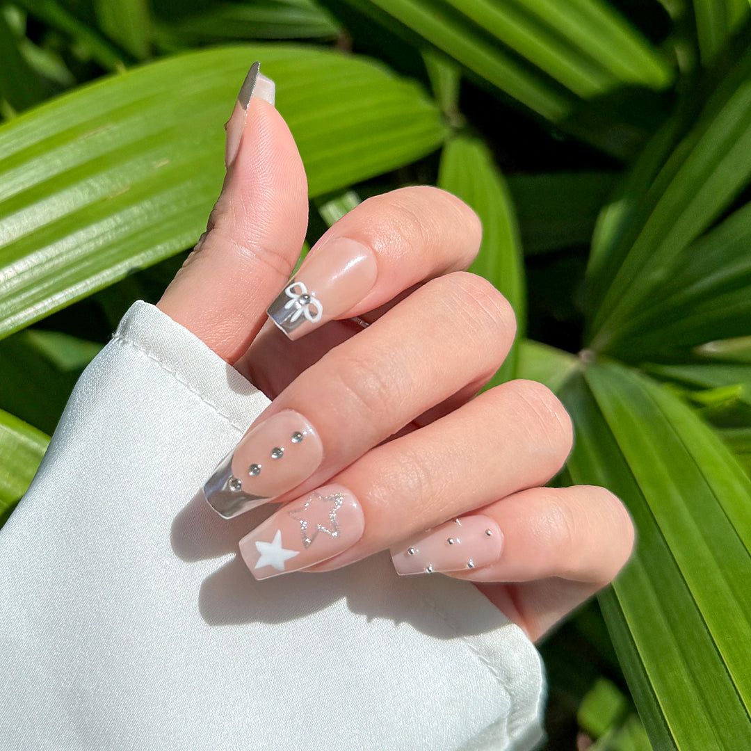 Handmade coffin-shaped press-on nails with metallic French tips, adorned with bow designs, rhinestones, and beads. A playful yet elegant style