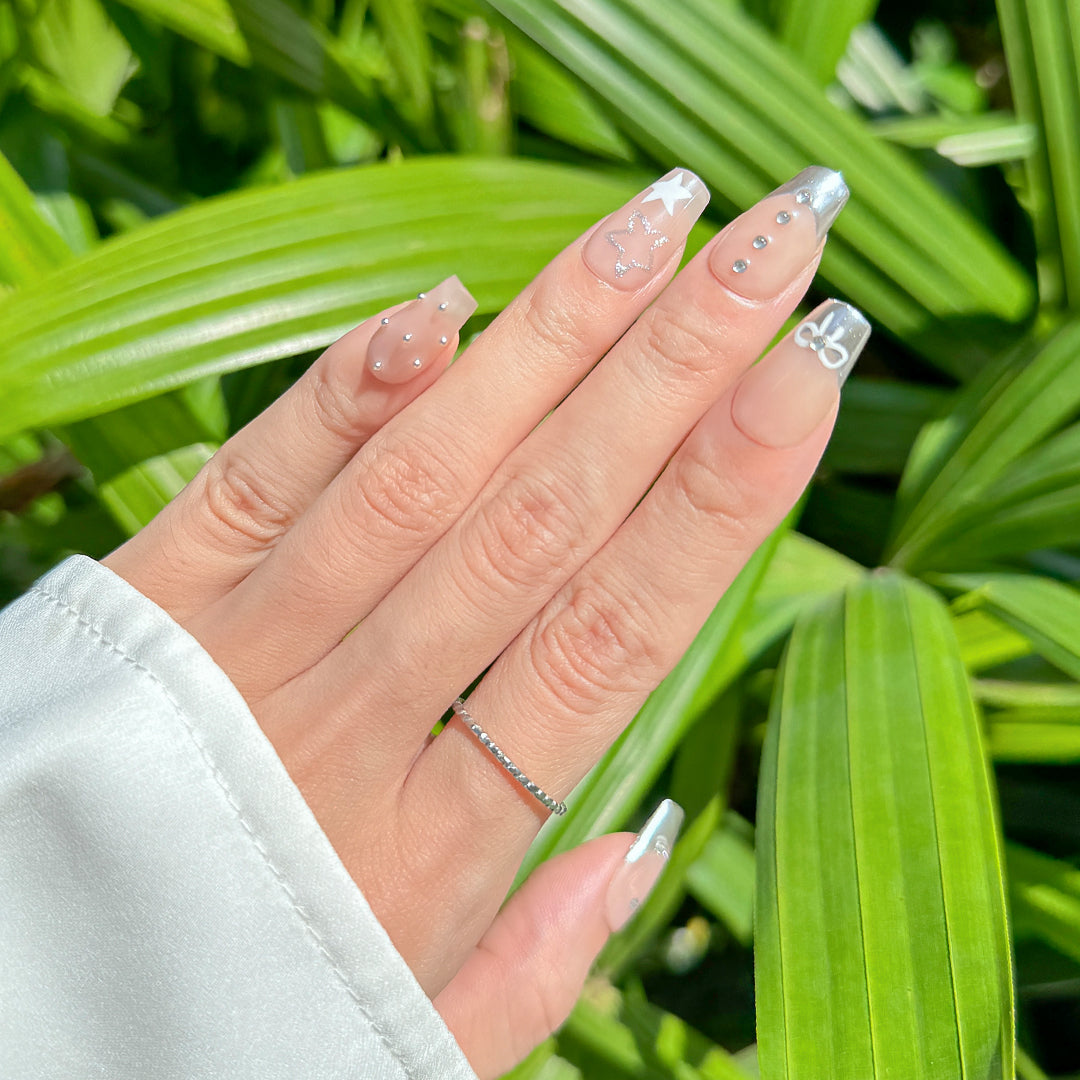 Handmade coffin-shaped press-on nails with metallic French tips, adorned with bow designs, rhinestones, and beads. A playful yet elegant style