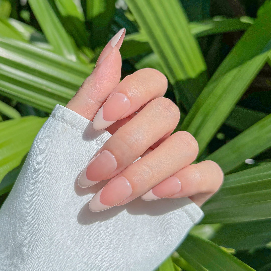 Handmade almond-shaped press-on nails with glossy nude-pink gradient French tips, offering a soft, elegant, and minimalist style.