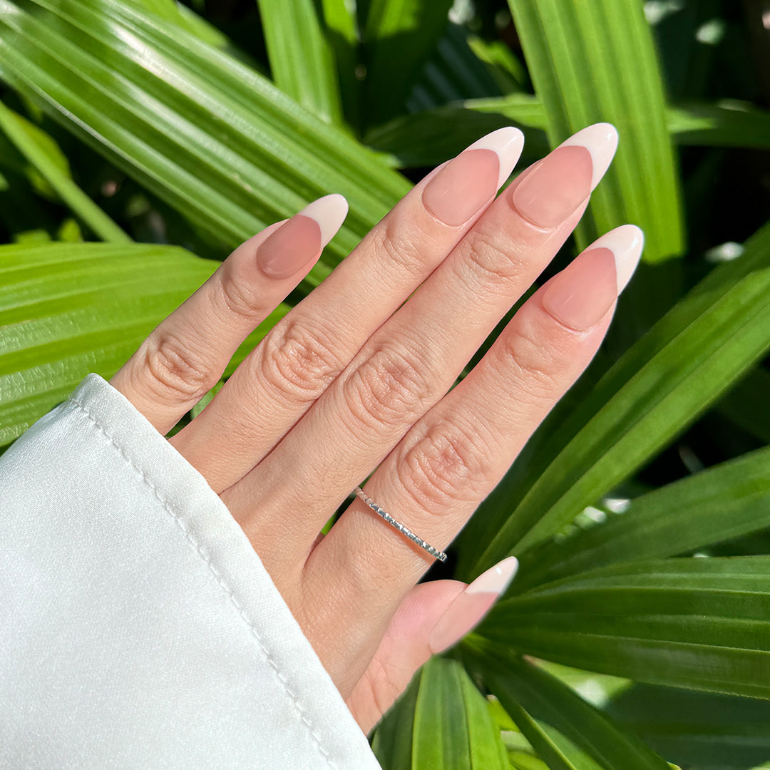 Handmade almond-shaped press-on nails with glossy nude-pink gradient French tips, offering a soft, elegant, and minimalist style.