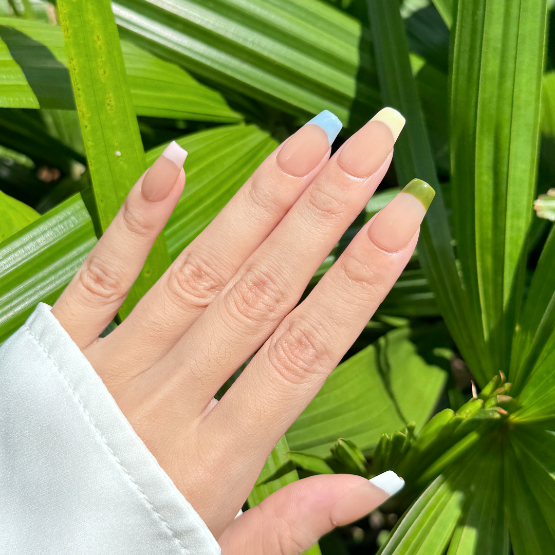 Handmade coffin-shaped sheer French press-on nails with colorful tips in red, pink, blue, green, white, and yellow.