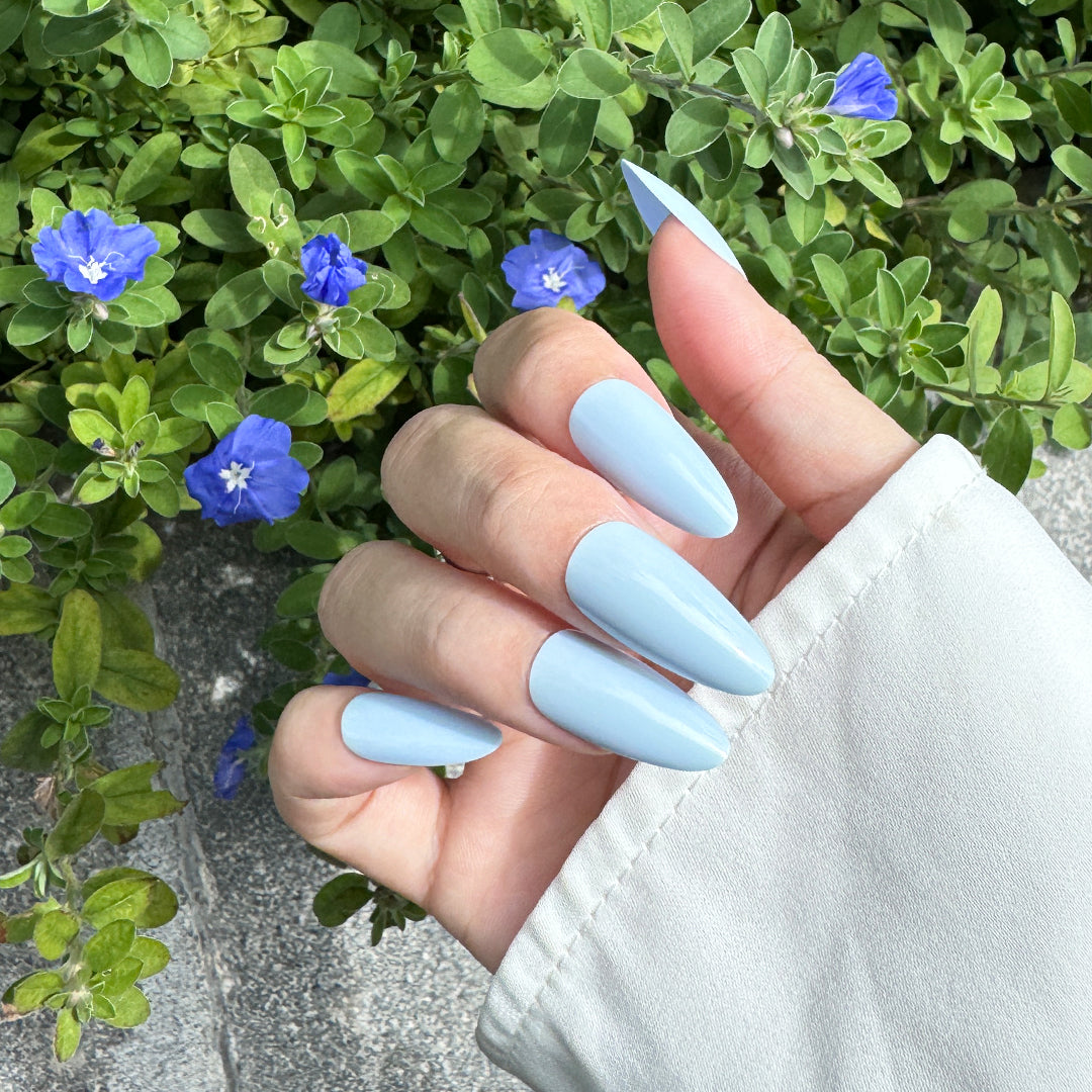 Glossy almond-shaped press-on nails in a creamy blue tone, offering a soft and dreamy finish.