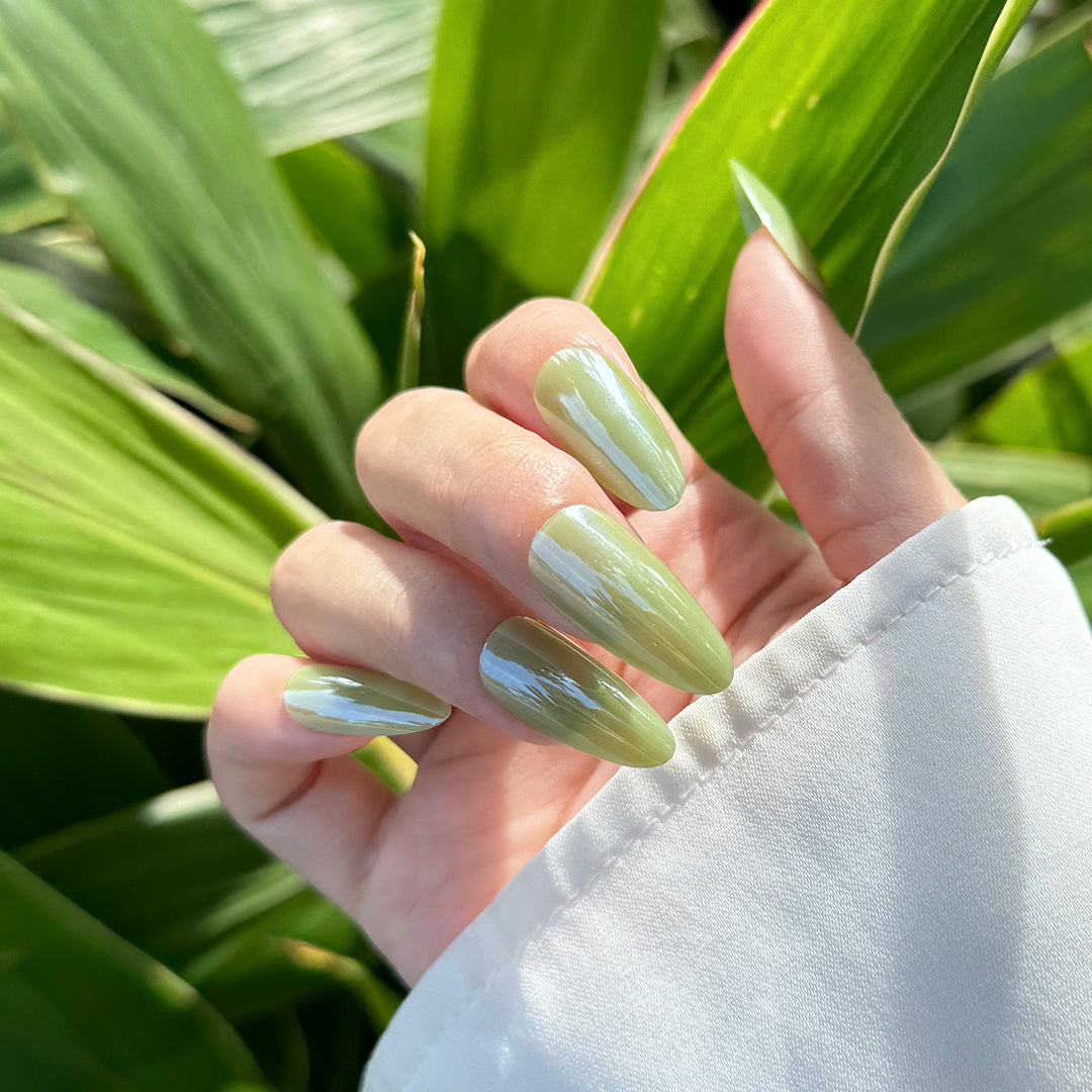 Satin glossy almond-shaped press-on nails in apple green for a fresh, trendy vibe.